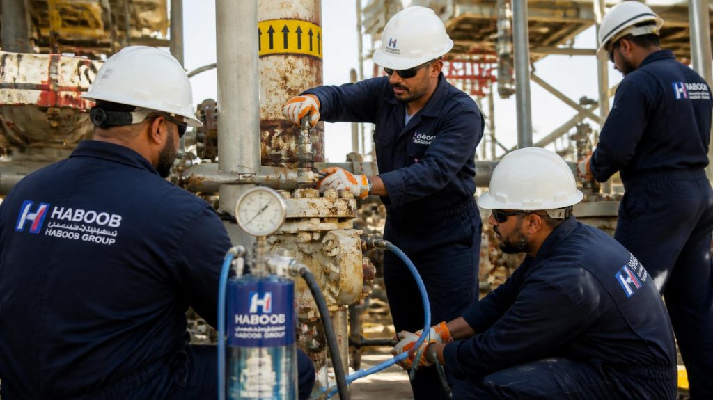 Haboob company technicians in branded coveralls performing valve injection and sealant repair under pressure, specialized equipment, oil and gas facility, professional photography (2)